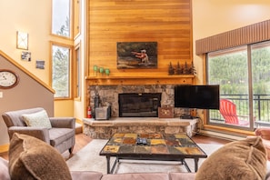Living area featuring a fireplace, cozy furnishings, and a mounted Smart TV + DVD player.
