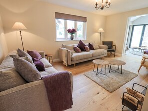 Living room with comfy seating for 8,  Woodburner & wall mounted 55" Smart TV