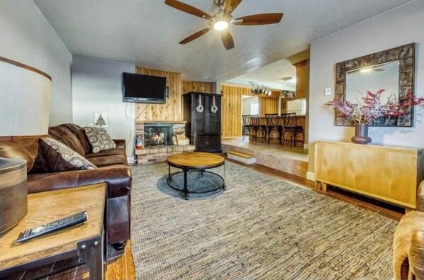 Step into this inviting living room where you'll find a cozy leather sofa and a charming fireplace, perfect for unwinding after a day of adventures. The tasteful decor and warm ambiance will make you feel right at home. (Main living area)
