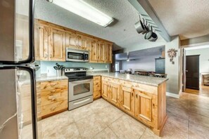 In this modern kitchen, you can channel your inner chef with stainless steel appliances and ample counter space. The rustic wood cabinetry adds a touch of charm, making meal preparation a delightful experience. (Full kitchen with modern appliances and bar seating)