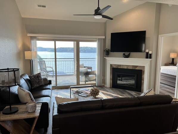 Open living area with two leather sofas, 70 inch Smart TV, lake view.