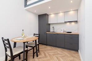 Kitchen with a modern design, a small dining table with two chairs, white cabinets, and wood-patterned flooring.