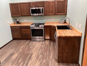 kitchen with gas range, convection oven, microwave oven with outside vent, touchless faucet, garbage disposal, and dishwasher