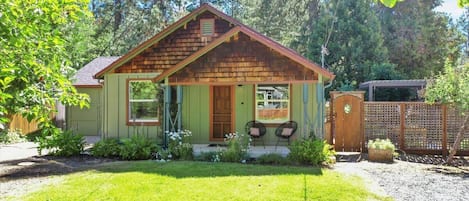 Sit a spell on this sweet covered front porch overlooking the flowers and lawn