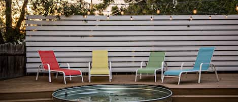 Stock tank pool at sunset, lounge chairs market lights.