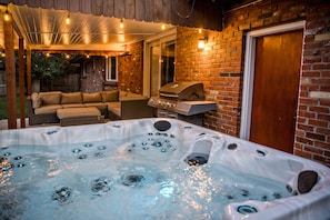 Hot tub facing patio with couch and market lights.