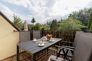A picturesque balcony furnished with a table and chairs, surrounded by lush greenery. Ideal for enjoying fresh air and relaxing outdoors.