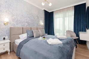 A bedroom featuring a queen-size bed with navy blue bedding and an elegant wallpaper accent wall. Curtains frame the window, creating a serene atmosphere.