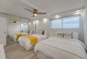 Bedroom with 2 queen size beds, ceiling fan, wicker dresser and bedside table, and large mirrored closet for storage