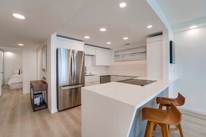Fully equipped kitchen with stainless steel appliances including refrigerator, freezer, dishwasher, microwave, dual Keurig/standard coffee maker, and electric stove top, and breakfast bar with 2 stools