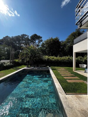 Jardin avec piscine face à la forêt.