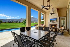 Covered patio features an outdoor dining table and a TV with plenty of seating.