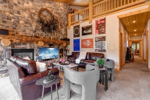 Main Level Living Room with plush leather sofas, contemporary arm chairs, smart tv, gas fireplace, vaulted ceilings, and private hot tub patio access