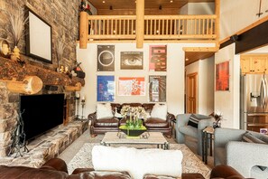 Main Level Living Room with plush leather sofas, contemporary arm chairs, smart tv, gas fireplace, vaulted ceilings, and private hot tub patio access