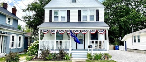 1920s, Victorian style home featuring a big front porch & patriotic bunting. 