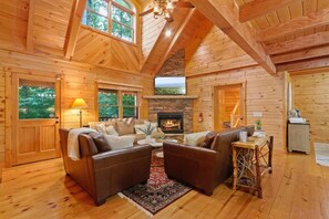 The ~3500 sq ft main cabin has 4 entertainment areas and this high-end living room with soaring vaulted ceiling, high stone mantle gas fireplace, 65" smart TV and the views of the Grandfather mountain and the surrounding forests.