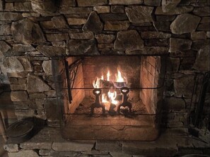 The beautiful stone wood burning fireplace with swing arm.