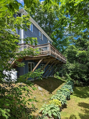 Rear view of house and large deck which faces the dock and water.