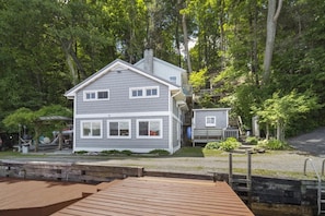 Cayuga Cottage, nestled lakeside surrounded by lush green.