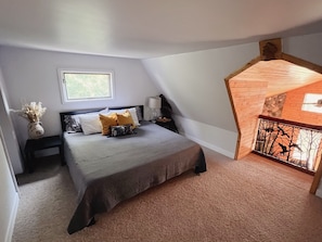 King bed in upstairs loft with a walk in closet and a smart tv. 