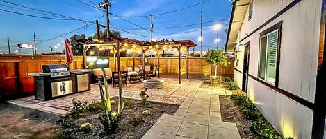 Outdoor pergola, grill, and fire pit at sunset