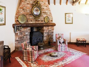 Fireplace is in the corner of the room so that the L-shaped room benefits from the heat that the wood burner throws out. | Lodge Farm Barn, South Walsham