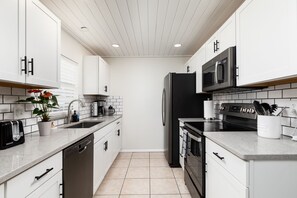 Updated kitchen fully stocked with cookware and utensils.