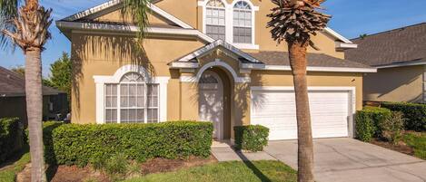 Front of the home features two palm trees and a well-manicured lawn.