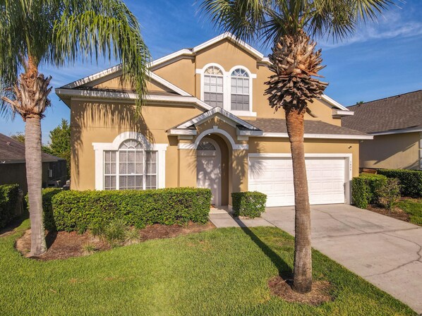 Front of the home features two palm trees and a well-manicured lawn. 