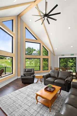 Main living space with vaulted ceilings, open floorplan, and an incredible wall of windows with views of Mount Snow.