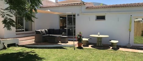 Garden area with corner sofa and round table with bench seats . 