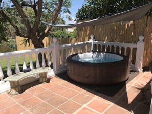Hot tub with sun sail and small bench seat.