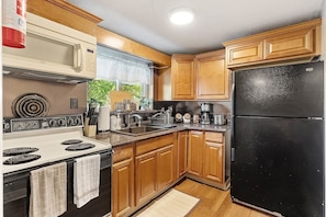 Full Kitchen with plenty of glasses, dishes, utensils in the top drawer by the fridge, nice natural light where your car is parked, large refrigerator, stove/oven and a mounted microwave.