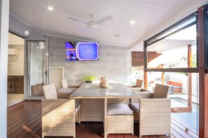 The large alfresco dining table has a TV for entertainment.