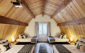 Open loft next to the main bedroom featuring 4 twin beds and projector TV.