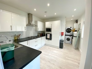 Bright spacious kitchen with microwave, hob, oven, fridge, utensils and pans.
Self-catering laundry area with iron and ironing board.