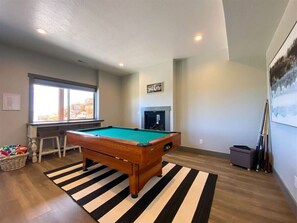 Amazing game room with pool table, fireplace, and natural light for endless indoor fun.