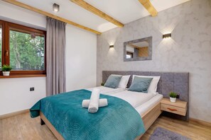 A bedroom featuring a large double bed with green bedding, complemented by wooden decor.