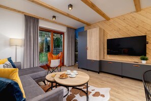 A cozy living room with a gray sofa, colorful pillows, and a mounted TV.
