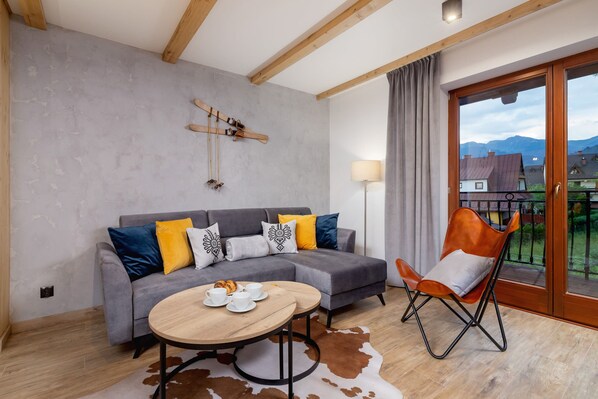 A cozy living room with a modern gray sofa, a wooden coffee table, and a stylish lamp.