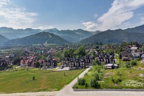 A beautiful panoramic view of a mountain village surrounded by lush greenery under a blue sky.