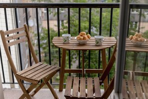 A charming balcony with a small table and chairs, perfect for enjoying coffee with a view of the greenery.