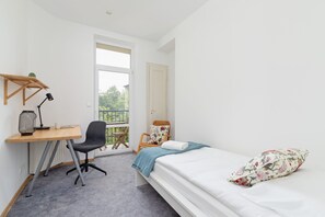 A serene bedroom featuring a bed and a functional desk by the window. Ideal for work or study in natural light.