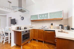 A cozy dining space with a wooden table and chairs next to the kitchen. The kitchen features white and wood tones, blending functionality with elegance.