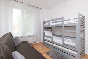 A bedroom with two bunk beds, perfect for families or groups. The room feels bright and inviting due to the light-colored walls and large window.