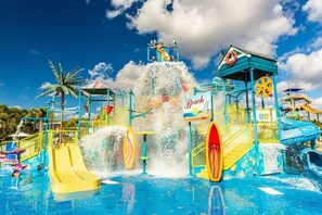 Kids' splash pad has slides and a bucket that dumps water.