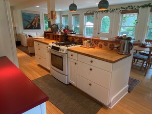 View of kitchen, cherry wood bar and dining room table behind.