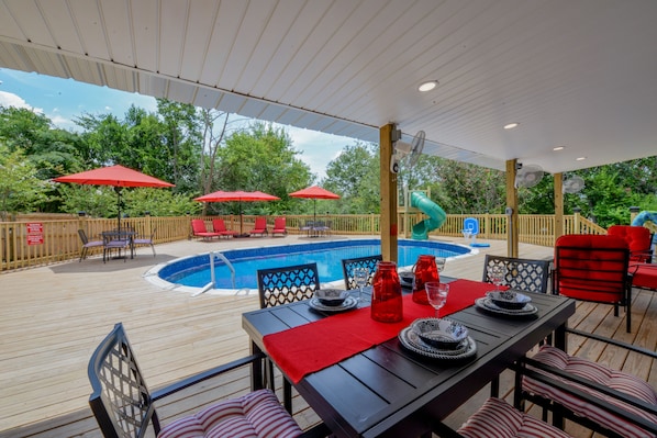 The Backyard - There is plenty to do at Bama Cottage! Out in the back there is a pool and water slide. There's also sun lounging chairs and a covered area for dining and grilling out.