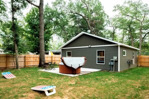 Spacious back yard with privacy fence, patio seating, hot tub, fire pit and corn hole boards
