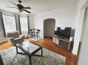 Natural light floods living room with full sofa, recliner and table top/chairs.